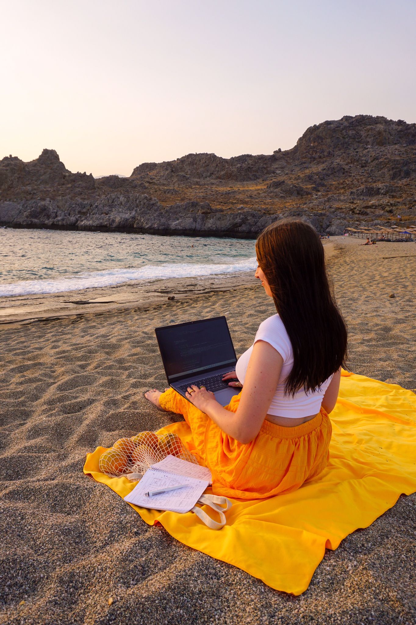 Anki sitzt mit Laptop am Strand